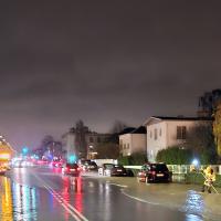 Vej med masser af vand på om aftenen med gadelamper og lys på lastbil